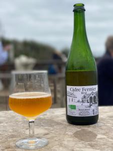 a glass of beer next to a bottle of wine at La maison bleue vacance et jardin, la mer à 550 m in Blainville-sur-Mer