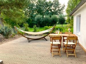 a hammock on a patio with a table and chairs at Moderner Bungalow im Seebad Bansin, 200 Meter zum Strand in Bansin