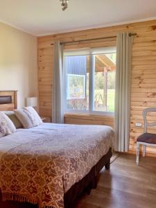 a bedroom with a bed and a large window at Hostal Vuelta al Sur in Puelo