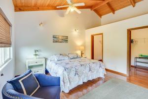 1 dormitorio con 1 cama y 1 silla azul en Hawaiian Retreat with Ocean Views in Captain Cook!, en Papa Bay Estates
