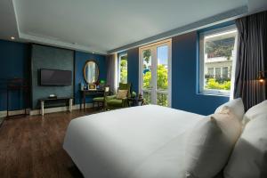 una camera da letto con un grande letto bianco e pareti blu di O'Gallery Premier Hotel & Spa a Hanoi