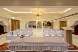 einen Bankettsaal mit weißen Stühlen und einem Tisch in einem Zimmer in der Unterkunft Treebo Trend Prasha in Nashik