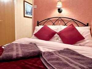 een bed met twee rode kussens erop bij Cheerful 2 Bedroom Home with Off-road parking in Deysbrook