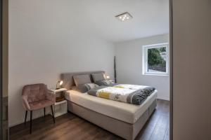 - une chambre avec un lit, une chaise et un miroir dans l'établissement Appartement Obkircher, à Nova Ponente