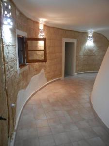 an empty room with a stone wall and a tile floor at Villa Trullo di Angela in Salve