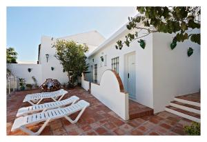 two white benches sitting on a brick patio at Hostal La Posada in Conil de la Frontera