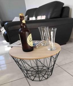 Una botella de cerveza en una mesa con dos vasos. en Gîte 2 pers en Saint-Pol-sur-Ternoise