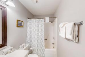 a white bathroom with a shower curtain and a sink at 3rd Avenue Oasis in Myrtle Beach +13 photos
