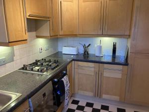 a kitchen with wooden cabinets and a stove top oven at Quiet 3 bed semi with off street parking in Bingham