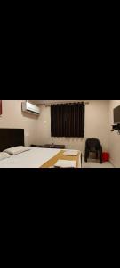 a room with two beds and a black chair at OYO Hotel Swagat Inn in Cuttack