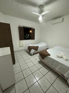 a bedroom with two beds and a tiled floor at Pousada 3 Pequis in Arraial d'Ajuda