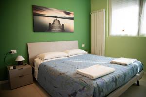 een groene slaapkamer met een bed met twee handdoeken erop bij Casa Fulvia in Rozzano