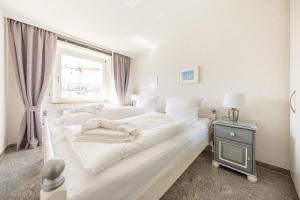 Cama blanca en habitación con ventana en Haus-Momoa-Duenenburg, en Westerland