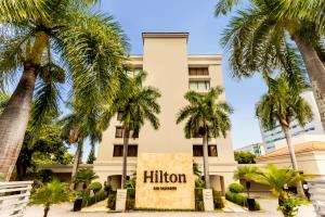 un hôtel avec des palmiers devant lui dans l'établissement Hilton San Salvador, à San Salvador