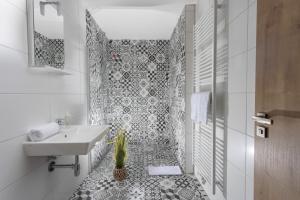 uma casa de banho com um lavatório branco e azulejos pretos e brancos. em Residence Morris Mladá Boleslav em Mladá Boleslav
