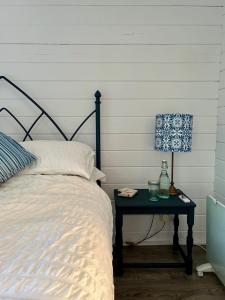 ein Schlafzimmer mit einem Bett und einem Tisch mit einer Lampe in der Unterkunft Driftwood Dreams Garden Cabin in Lyminster