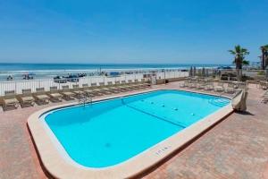 uma piscina com cadeiras e a praia ao fundo em Fantasy Island Resort I em Daytona Beach Shores