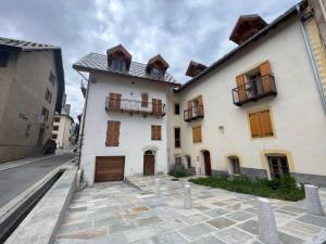 un gran edificio blanco con puertas y ventanas de madera en Saint Eldrade, en Le Monêtier-les-Bains