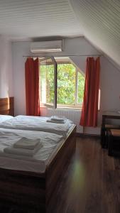 a bedroom with a bed and two windows with red curtains at Ardilla in Lhota