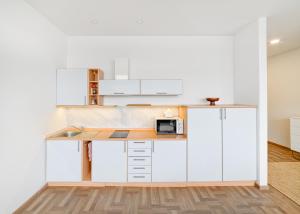 a kitchen with white cabinets and a counter with a microwave at Apartament 502 in Kaunas