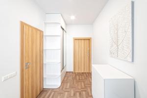 a hallway with white walls and a wooden door at Apartament 502 in Kaunas