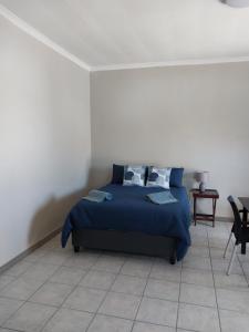 ein Schlafzimmer mit einem blauen Bett und Fliesenboden in der Unterkunft 13 Steps in Springbok