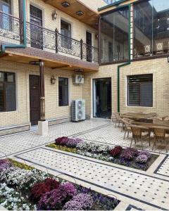 a patio with a table and flowers in front of a building at VOSTOK HOTEL in Bukhara