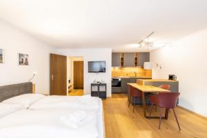 a bedroom with a bed and a table and a kitchen at 7304 Pure Freude in dieser stilvoll renovierten Wohnung mit moderner Kueche in Vulpera