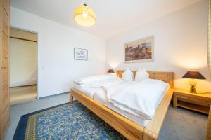 a bedroom with a bed with white sheets and a blue rug at 8001 Gemuetliche 2,5-Zimmer-Wohnung mit wunderschoenem Ausblick Richtung Scuol in Vulpera