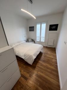 1 dormitorio con cama blanca y suelo de madera en Beau 3 pièces aux portes de PARIS, en Charenton-le-Pont