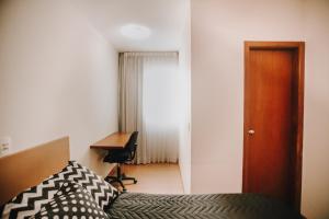 Confortável apartamento na Savassi. في بيلو هوريزونتي: غرفة نوم بسرير ومكتب وباب
