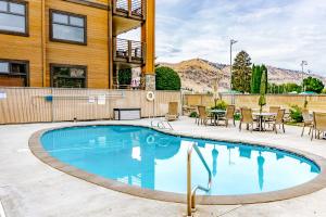 a swimming pool with tables and chairs next to a building at Driftin' Cabanas in Chelan
