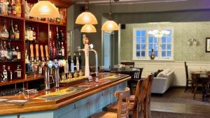 un bar con un montón de botellas de alcohol en The Cricketers Inn, en Winchester