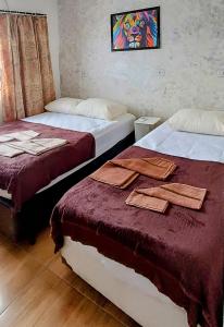 Habitación con 2 camas y toallas. en Casa da Lú - Praia e Piscina en Praia Grande
