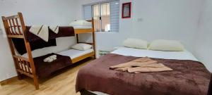 a bedroom with two bunk beds and a towel on the bed at Casa da Lú - Praia e Piscina in Praia Grande