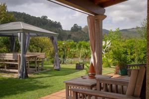 an outdoor patio with tables and an umbrella at Casa Rural Pontevedra con piscinajardínbarbacoa in Pontevedra