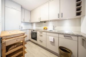 una cocina con armarios blancos y fregadero en PL 204 Geraeumige 3,5-Zimmer-Wohnung im Haus Plavna mit grossem Balkon, en Vulpera