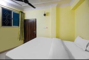 Un dormitorio con una gran cama blanca y una puerta en POP Oyo Flagship Moon Light Hotel, en Ranchi