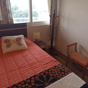 1 dormitorio con cama con almohada de mariposa y silla en Departamento Pacifico, en La Serena