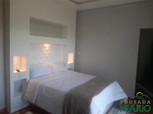 a bedroom with a large white bed with two lights at Pousada Hilário in São João del Rei