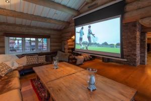 a living room with a large screen television in a log cabin at Chalet De Luxe 518 in Trysil