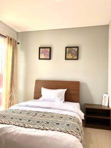 a bed in a bedroom with three pictures on the wall at Behomy Corner Eight Lippo Karawaci in Tangerang