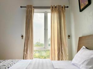 a bedroom with a bed and a window with curtains at Behomy Corner Eight Lippo Karawaci in Tangerang