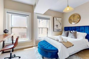 a bedroom with a blue bed and a desk and a clock at Chic River North Retreat in Chicago