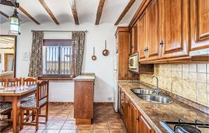 una cocina con armarios de madera, mesa y fregadero en Casa Triana en Cuevas del Campo