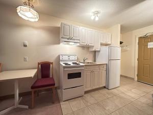 a kitchen with white appliances and a table and a chair at Western Budget Motel Ponoka in Ponoka