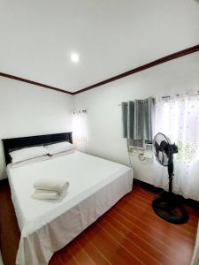 a bedroom with a white bed and a fan at Calapan Transient House Acacia L35 in Calapan