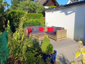 a patio with a couch with red pillows on it at Gemütliche Gäste-/Messewohnung 350 m. zur S-Bahn in Röthenbach an der Pegnitz