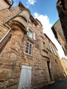 um velho edifício de pedra com uma porta ao lado em La Maison des Echevins em Vabres-lʼAbbaye