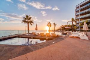 una piscina del resort con sedie, palme e l'oceano di Suite BM - 3 Pools-Gym-AC-Huge Balcony Sea View a Funchal